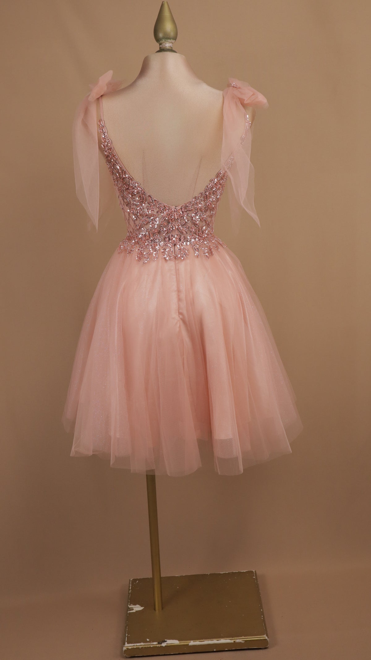 Vestido de fiesta corto en corte A de tul con corpiño de pedrería y lazos al hombro.