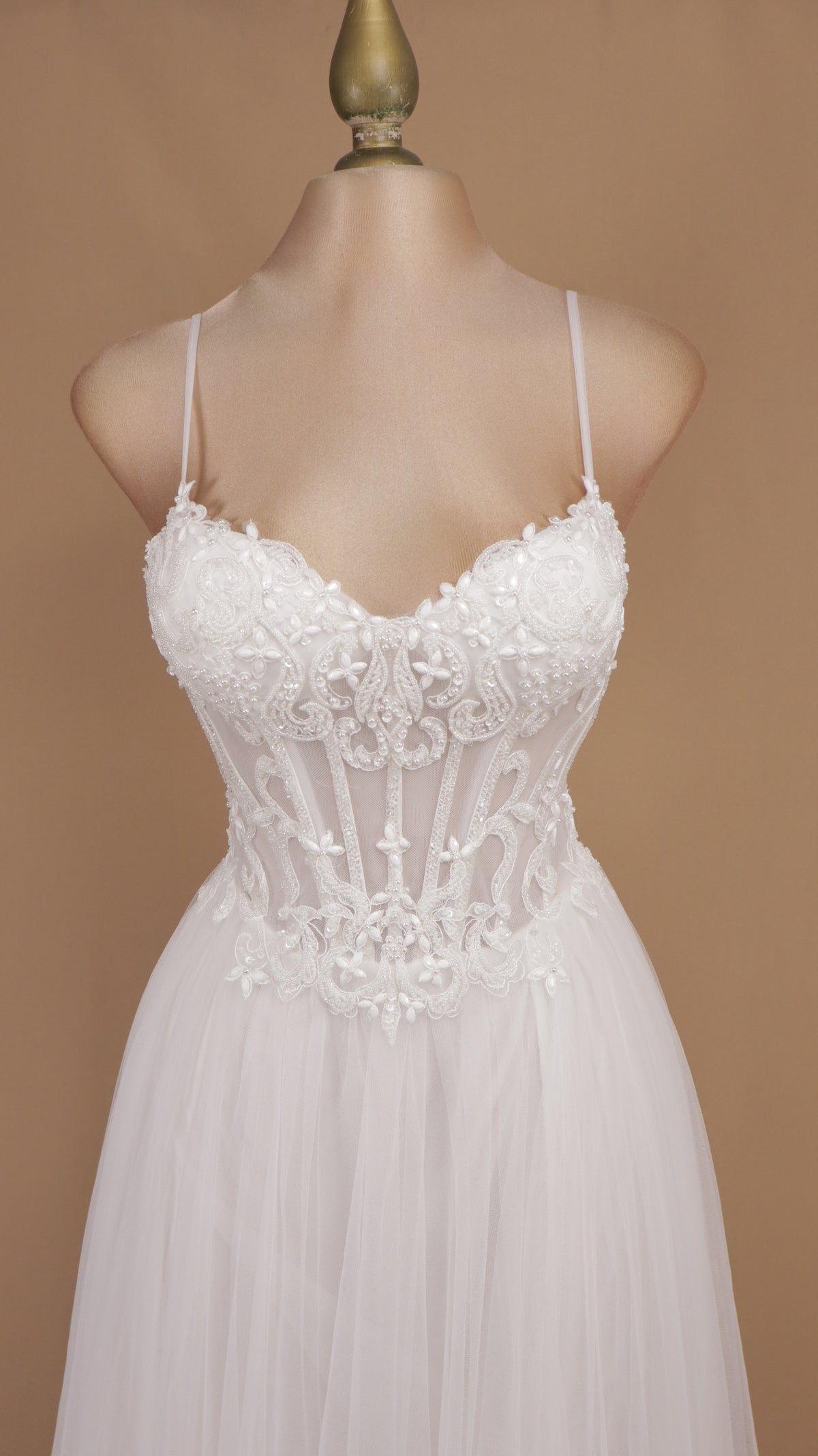 Vestido de novia con corsé translúcido de encaje, pedrería y falda fluida de tul