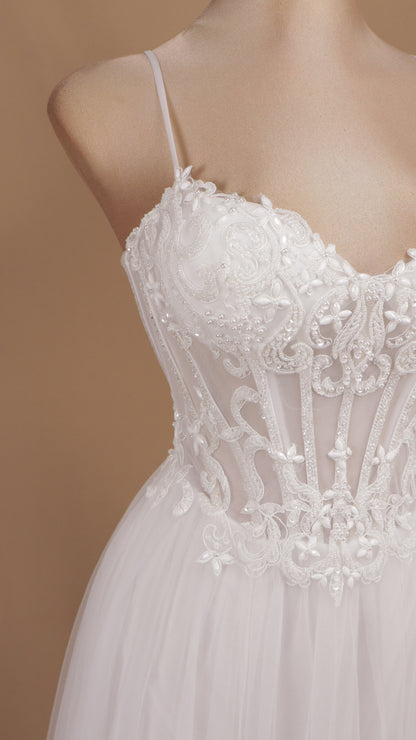 Vestido de novia con corsé translúcido de encaje, pedrería y falda fluida de tul