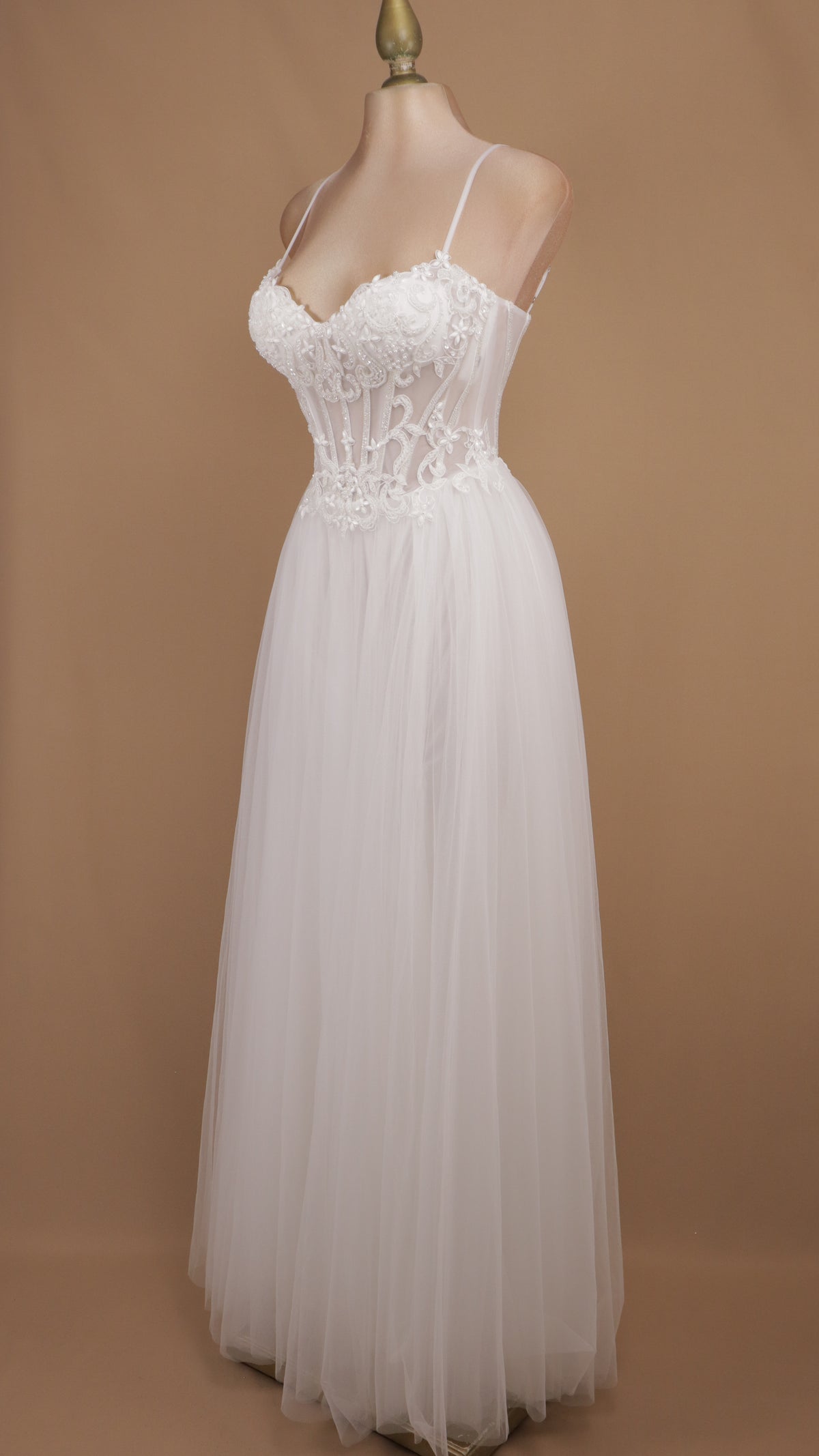 Vestido de novia con corsé translúcido de encaje, pedrería y falda fluida de tul