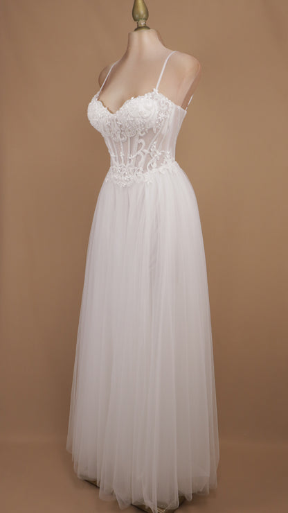 Vestido de novia con corsé translúcido de encaje, pedrería y falda fluida de tul