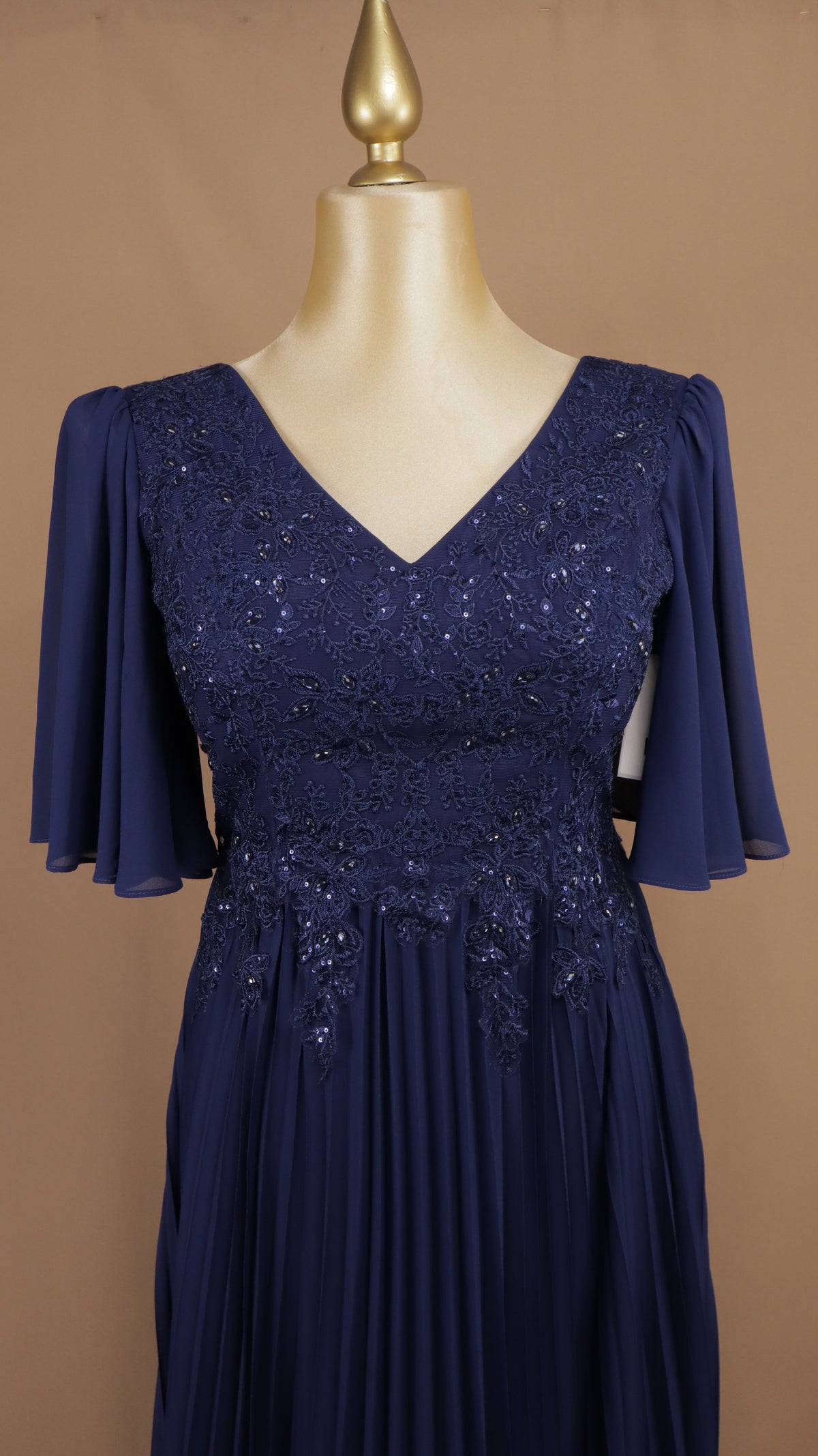 Vestido de noche en gasa plisada con encaje, bordado y mangas campanilla