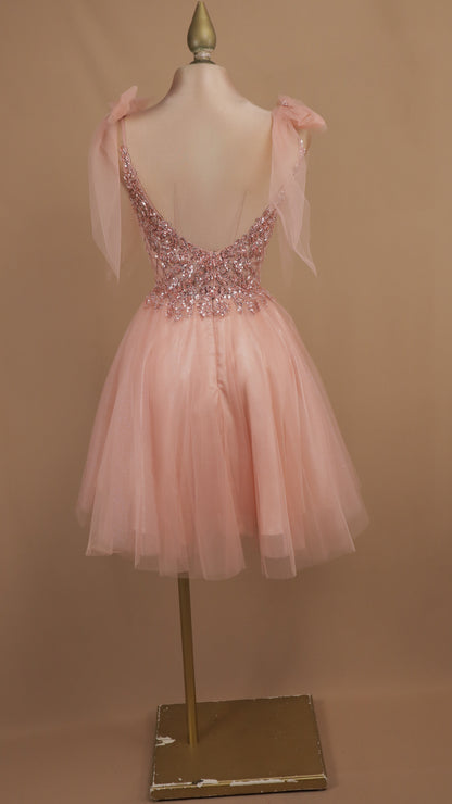Vestido de fiesta corto en corte A de tul con corpiño de pedrería y lazos al hombro.