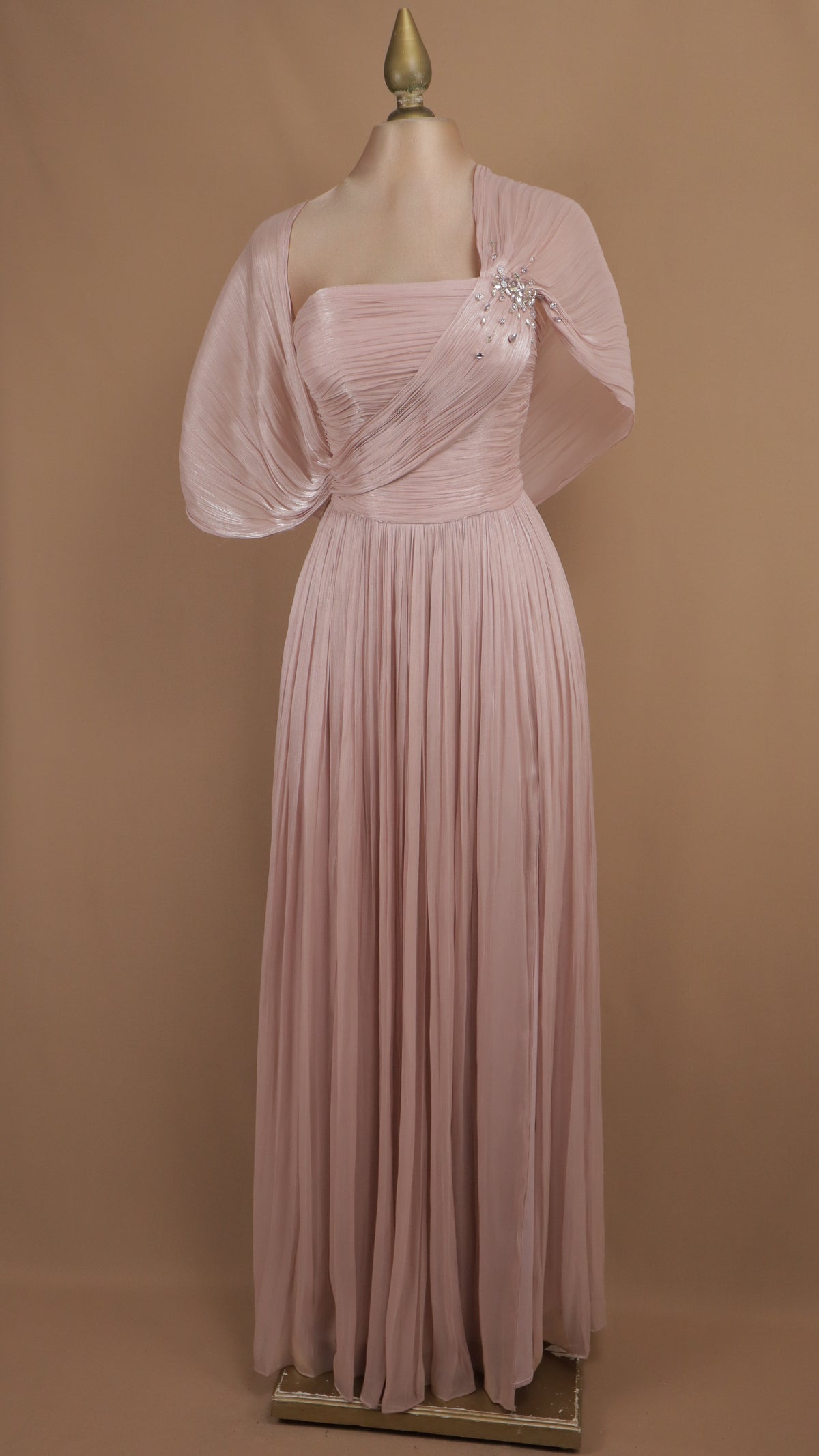 Vestido de gala largo plisado con escote y capa drapeada.